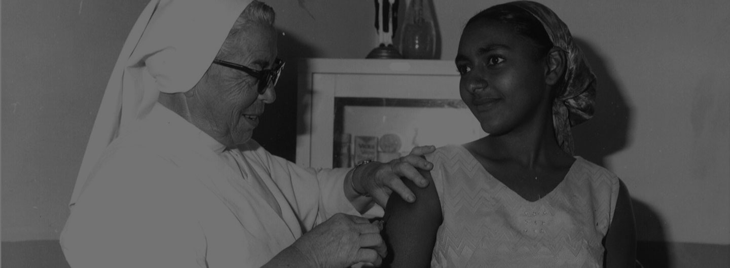 A historical photo from CMMB archives featuring a woman receiving a vaccination.